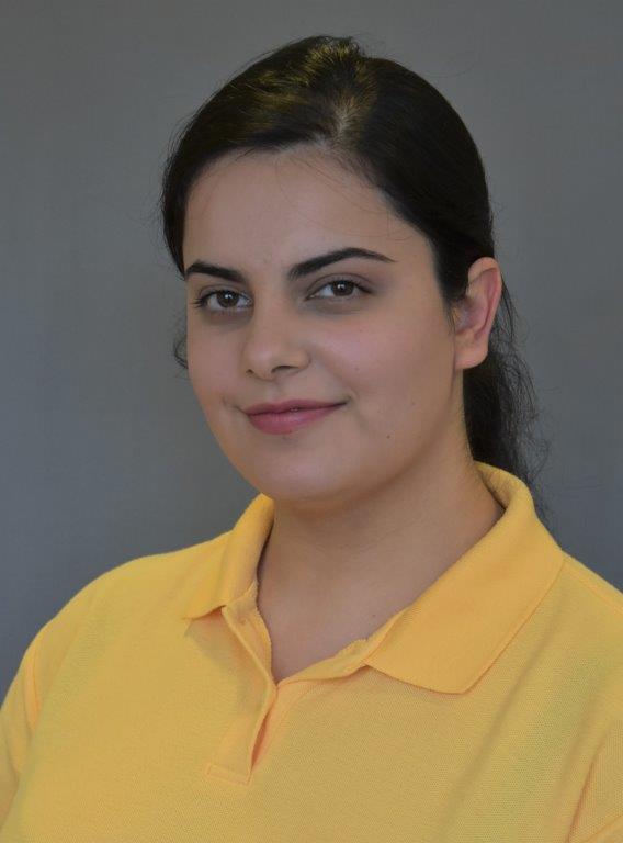 Portrait von Bana Abdulqahar in einem gelben Poloshirt. Sie trägt ihre dunklen Haare in einem Zopf und lächelt in die Kamera