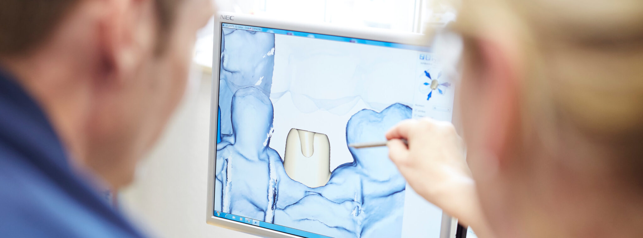 Zwei Personen, die sich über ein 3D-Modell auf einem Monitor unterhalten